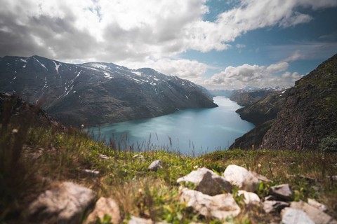 A breathtaking view of a serene turquoise lake nestled between rugged mountains in Norway The