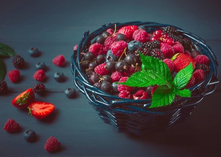 Mix of fresh berries, in a basket, on a wooden gray table, no people, top view
