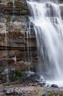 Little hiker in front of large Cascata di Mezzo waterfall, long exposure, Vallesinella, Brenta,