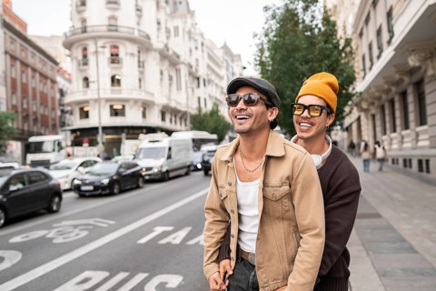A joyful colombian gay couple enjoying a casual city walk. Both are wearing sunglasses and