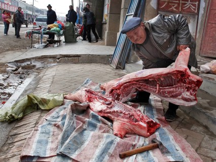 Xining, CHN, 27/02/09 - A butcher cuts up a side of pork on the pavement of a village near Xining.