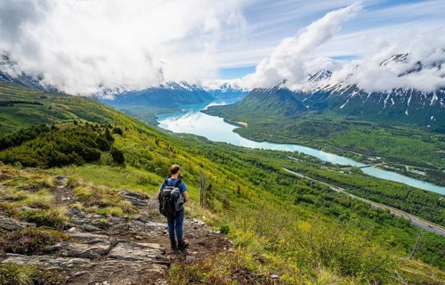 Climbers on a hiking trail, Slaughter Ridge Trail, view of snowy mountains and turquoise lake Kenai
