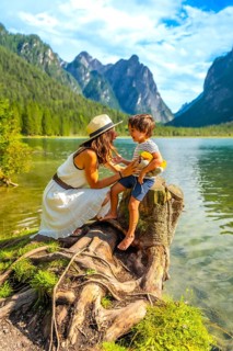 Mother and son sharing a playful moment by an alpine lake, surrounded by the breathtaking scenery