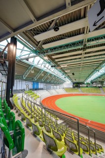 Interior view of an empty stadium with green rows of seats and an athletics track, Glaspalast,