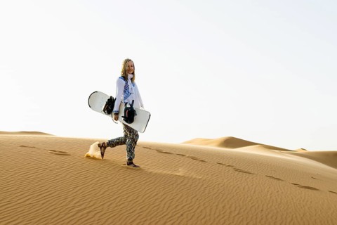 Young woman with snowboard in the sand dunes, near Merzouga, Meknès-Tafilalet region, Erg Chebbi,