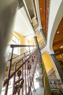 Historic staircase with arches and columns. Light falls through the windows, the structure looks