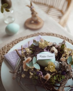 Top view of an elegantly arranged Easter table setting featuring naturally dyed eggs nestled in a