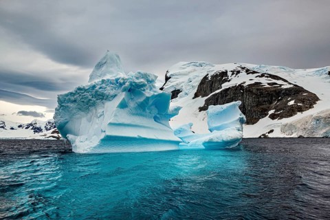 Large iceberg in the cold sea with snow-covered sky and dramatic atmosphere, icebergs in the