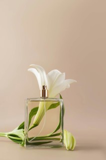 A minimalist perfume bottle elegantly paired with a white lily flower against a neutral background,
