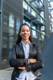 Vertical portrait of a proud latin businesswoman smiling with arms crossed standing in the city