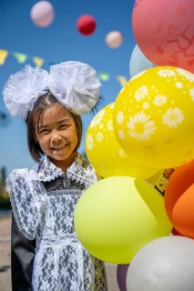 Happy schoolgirl with colourful balloons on the first day of school, Issyk-Kul region, Kyrgyzstan