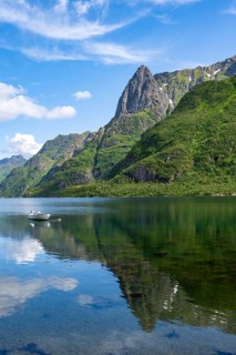 Small boats at the fjord Austnesfjorden, idyllic Norwegian fjord landscape, mountains reflected in
