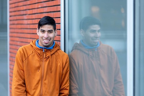 A person reflects calmly while leaning against a window at a mental health leisure center. Their