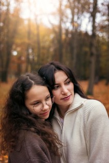 A warm embrace between a mother and daughter amidst the golden autumn foliage, capturing a tender