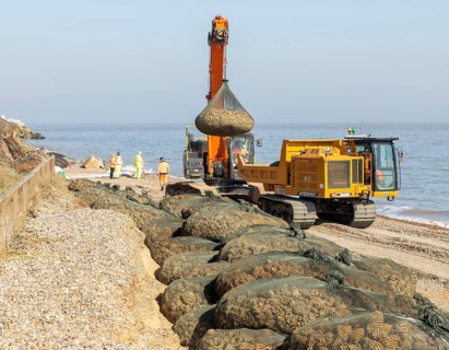 Emergency coastal defences work placing rock bags on beach to protect property, North Sea coast,