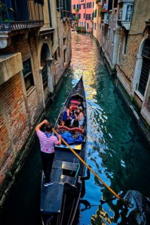 VENICE, ITALY, JUNE 27, 2018: Narrow canal between colorful old houses with gondola boat with