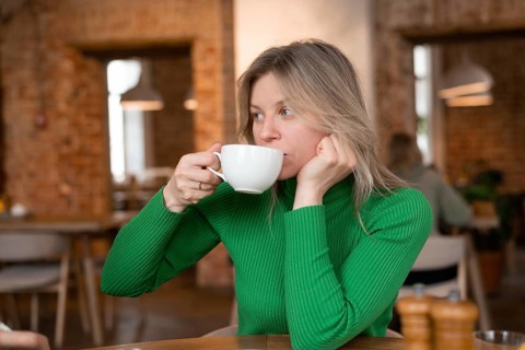 Woman enjoys a relaxing morning at a cozy cafe, sipping coffee. The warm interior ambiance adds to