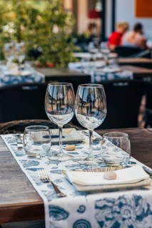 Set of glasses with white wine and plates placed on table with tablecloth on table