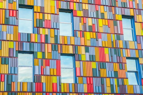 A detailed view of a building facade covered in a multitude of brightly colored panels arranged in