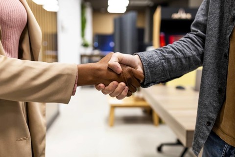 Two people are shaking hands in a modern office. The image captures the essence of professionalism,