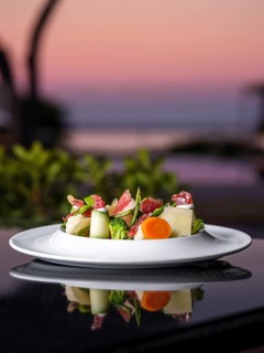 A beautifully arranged gourmet salad with ham featuring fresh vegetables and cheese. The elegant