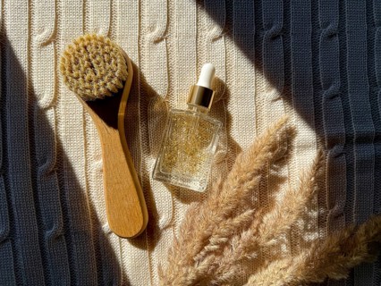 A wooden brush and serum cosmetic bottle with golden serum rest on textured fabric, enhanced by