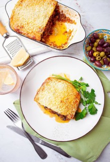 Moussaka served with olives, in a bright kitchen setting, homemade, no people
