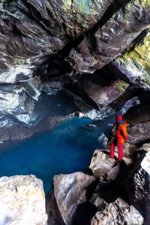 A man in the Grjotagja volcanic cave with hot thermal water near Lake Myvatn, Iceland