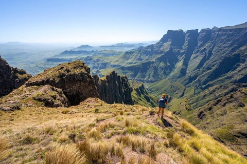 Young hiker looking at the impressive mountains and cliffs of the Drakensberg Mountains, hiking