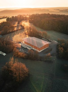 A building surrounded by trees in the warm light of an autumn sunset seen from the air, Gechingen,