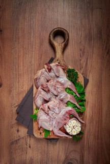 Raw quail meat, on a cutting board, with spices and herbs, top view