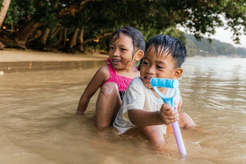 Two cheerful children enjoy playing in the shallow waters of a Philippine beach, with laughter and