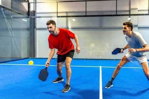 Two male players engaging in an active game of pickleball, holding paddles and focusing on the