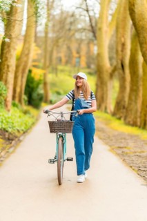 Happy young woman walking with her vintage bicycle in a park, enjoying a sunny day of leisure