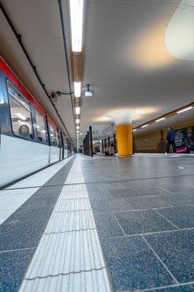 Close-up of an underground railway track with incoming train and bright lighting, Hamburg, Germany