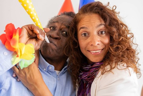 A joyful moment at a birthday celebration featuring two people wearing colorful party hats and