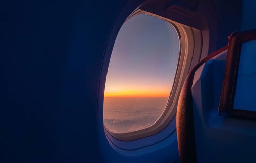 A breathtaking view of a sunrise from an airplane window, capturing the rich orange and blue hues