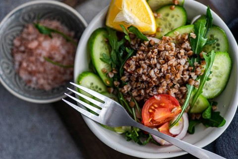 A nutritious lunch is prepared with fresh rocket, chopped oregano, cherry tomatoes, cucumber,