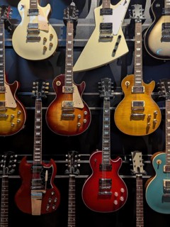 A collection of electric guitars displayed on a wall. Each guitar showcases a unique design and