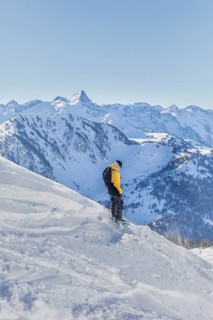 A snowboarder in a yellow jacket enjoys the snowy slopes with stunning mountain views. Bright