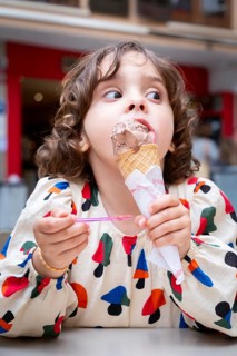 A young girl delights in a chocolate ice cream cone, savoring every bite on a sunny day in a