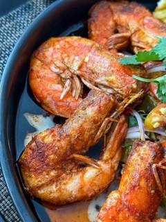 Close up of flavorful dish of seasoned fried shrimp served with a spicy dipping sauce in a Thai