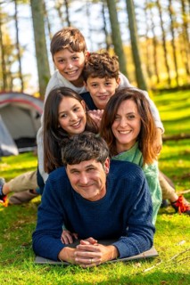 Caucasian family having fun together lying on the forest one on top of each other next to camping