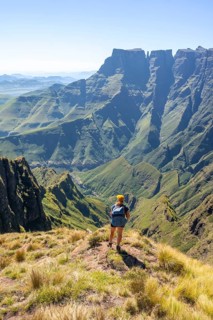 Young hiker looking at the impressive mountains and cliffs of the Drakensberg Mountains, hiking