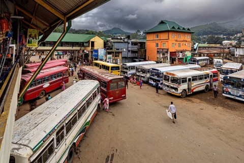 Several buses at a bus stop with people and mountainous landscape in the background, Nuwara Eliya