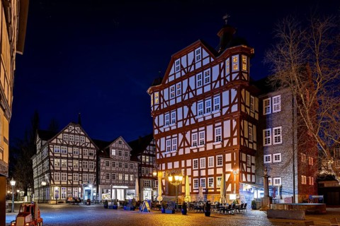Impressive half-timbered houses in their nocturnal splendour with lights on a quiet square, The