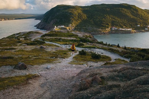 Back view of an unrecognizable person walking along a rugged trail with a panoramic vista of Signal