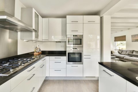 A contemporary kitchen featuring sleek stainless steel appliances, glossy white cabinets, and a