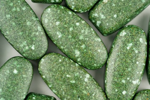 Close-up of green pills scattered on white background