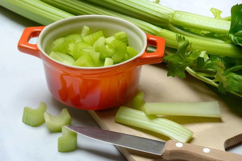 Celery stalks, pieces in pots with kitchen knife